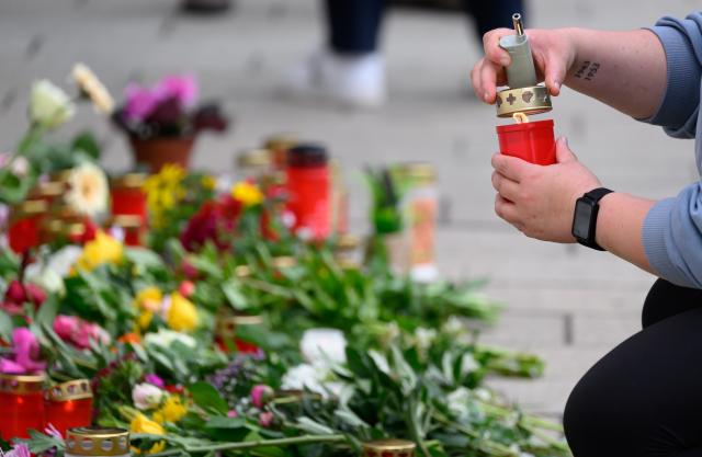 05 May 2026, Saxony, Leipzig: A woman lights a candle at the memorial site in front of the university's Paulinum following a reckless driving spree that left two people dead and three seriously injured. A 33-year-old German citizen had driven into the busy pedestrian zone on Monday afternoon. Photo: Hendrik Schmidt/dpa