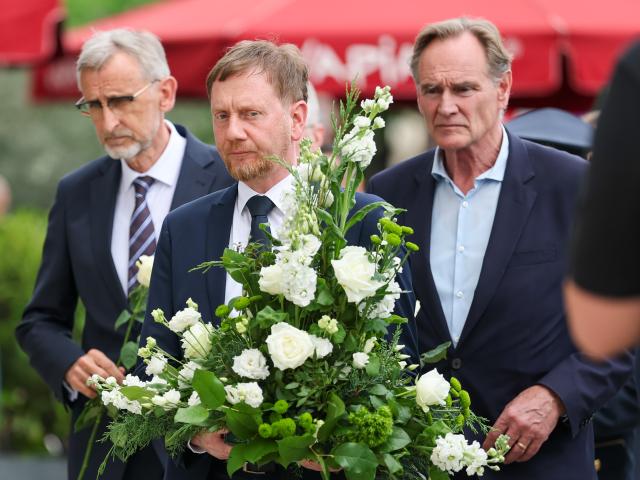 05 May 2026, Saxony, Leipzig: (R-L) Burkhard Jung, Lord Mayor of Leipzig, Michael Kretschmer, Minister President of Saxony, and Armin Schuster, Minister of the Interior of Saxony, lay flowers at the memorial site. The previous day, a 33-year-old German citizen had driven through the pedestrian zone in Grimmaische Strasse on a rampage. Two people were killed and three seriously injured. Photo: Jan Woitas/dpa