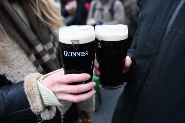 FILED - 16 March 2025, Bavaria, Munich: Participants in the St. Patrick's Day Parade for the Irish national holiday hold beer glasses containing Guinness beer near Odeonsplatz. Photo: Felix Hörhager/dpa
