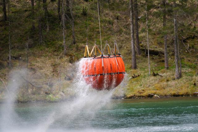 06 May 2026, Bavaria, Ruhpolding: A helicopter lifts a water tank from a lake to help fight the large-scale wildfire on the 1,270-meter-high Sauruesselkopf in the Chiemgau Alps. Photo: Uwe Lein/dpa
