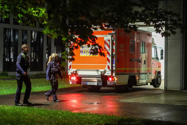 06 May 2026, Duesseldorf: Police officers walk past an ambulance carrying a German patient who has been evacuated from the hantavirus-hit cruise ship MV Hondius, to the infection center at Duesseldorf University Hospital. Photo: Christoph Reichwein/dpa