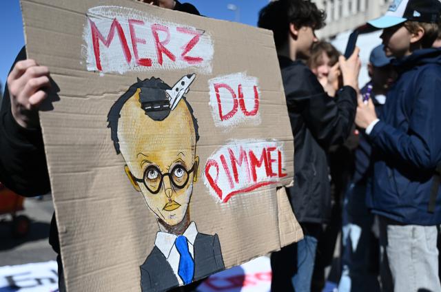 08 May 2026, Hamburg: A demonstrator holds up a sign with explicit language directed at German Chancellor Friedrich Merz as people gather in front of the Brandenburg Gate in Berlin to protest against the draft. Photo: Katrin Luxenburger/dpa