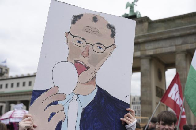 08 May 2026, Berlin: A demonstrator holds up a sign with explicit language directed at German Chancellor Friedrich Merz as people gather in front of the Brandenburg Gate in Berlin to protest against the draft. Photo: Sven Kaeuler/dpa