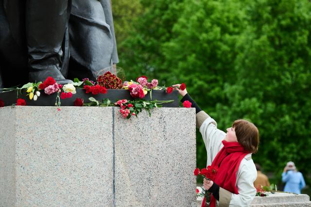 08 May 2026, Berlin: A woman lays a carnation at the Soviet War Memorial in Treptower Park, commemorating the liberation from National Socialism. Photo: Annette Riedl/dpa