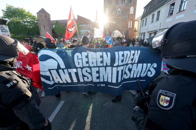 08 May 2026, Mecklenburg-Western Pomerania, Demmin: Police officers stand in front of a road blockade by counter-demonstrators during the the so-called funeral march by Right-wing extremists, organized by the The Homeland
(Die Heimat) party. Photo: Bernd Wüstneck/dpa