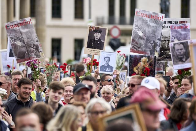 09 May 2026, Berlin: Participants stand in front of the Brandenburg Gate during a memorial march honoring Soviet soldiers who died in the Second World War. Photo: Michael Ukas/dpa