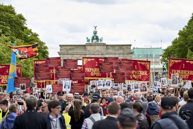 09 May 2026, Berlin: Participants stand in front of the Brandenburg Gate during a memorial march honoring Soviet soldiers who died in the Second World War. Photo: Michael Ukas/dpa