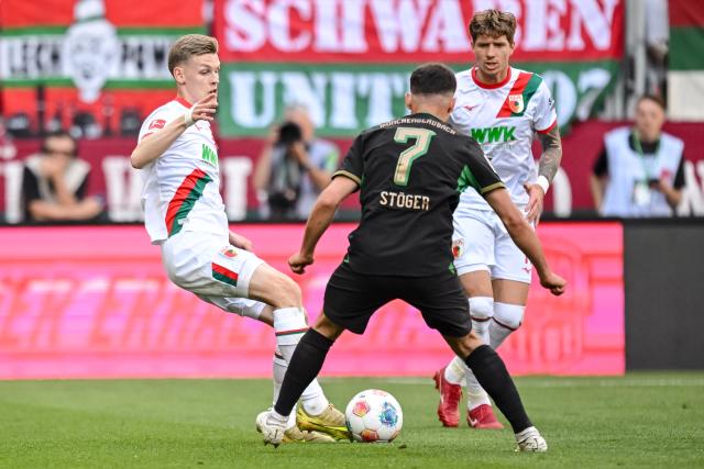 09 May 2026, Bavaria, Augsburg: Augsburg's Anton Kade (L) and Kristijan Jakic in action against Borussia Moenchengladbach's Kevin Stoeger (C) during the German Bundesliga soccer match between FC Augsburg and Borussia Moenchengladbach at the WWK-Arena. Photo: Harry Langer/dpa - IMPORTANT NOTICE: DFL and DFB regulations prohibit any use of photographs as image sequences and/or quasi-video.