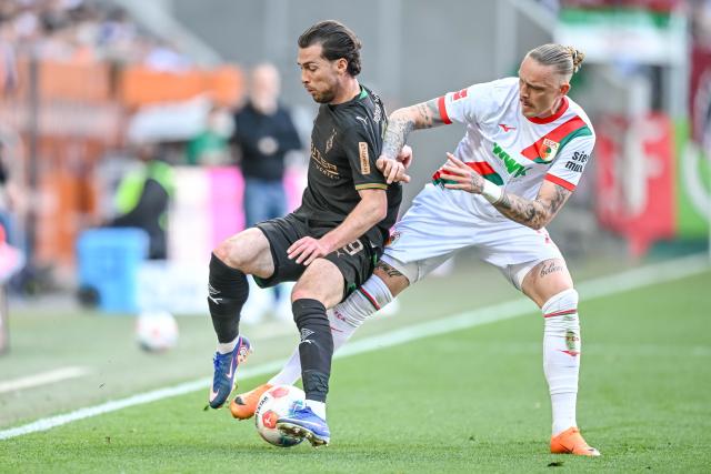 09 May 2026, Bavaria, Augsburg: Borussia Moenchengladbach's Joe Scally and Augsburg's Marius Wolf battle for the ball during the German Bundesliga soccer match between FC Augsburg and Borussia Moenchengladbach at the WWK-Arena. Photo: Harry Langer/dpa - IMPORTANT NOTICE: DFL and DFB regulations prohibit any use of photographs as image sequences and/or quasi-video.