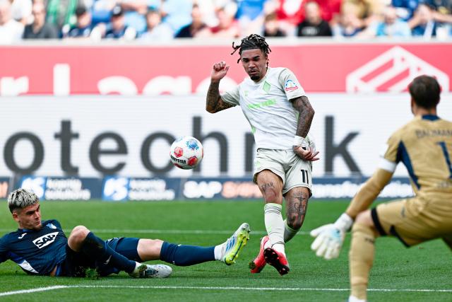 09 May 2026, Baden-Württemberg, Sinsheim: Werder Bremen's Justin Njinmah (C) in action against Hoffenheim's Albian Hajdari (L) and goalkeeper Oliver Baumann during the German Bundesliga soccer match between TSG 1899 Hoffenheim and Werder Bremen at the PreZero Arena. Photo: Uwe Anspach/dpa - IMPORTANT NOTICE: DFL and DFB regulations prohibit any use of photographs as image sequences and/or quasi-video.