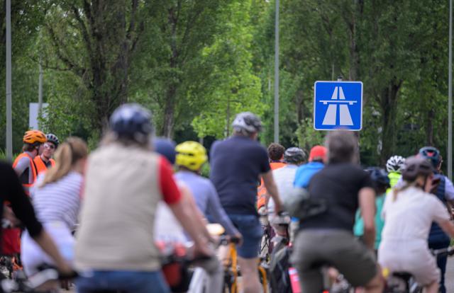 10 May 2026, Hesse, Frankfurt_Main: Cyclists ride in front of a highway sign during a demonstration against the planned expansion of the A5 freeway. Photo: Hannes P. Albert/dpa