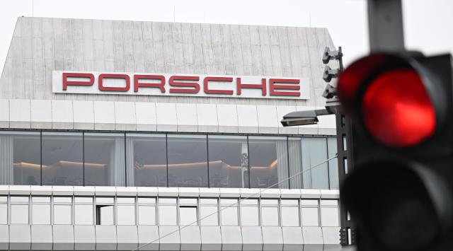 FILED - 10 October 2025, Baden-Wuerttemberg, Stuttgart: A red traffic light shines in front of a building bearing the Porsche logo at the sports car manufacturer's headquarters in Stuttgart-Zuffenhausen. Photo: Bernd Weißbrod/dpa
