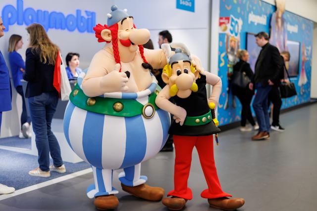 FILED - 30 January 2024, Bavaria, Nuremberg: FILE PHOTO - Two actors dressed as the comic book characters Asterix (R) and Obelix stand at the Playmobil booth during the 73rd International Toy Fair. Photo: Daniel Karmann/dpa