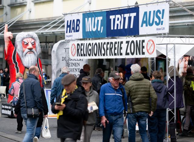 14 May 2026, Bavaria, Wuerzburg: An information booth bearing the slogans 'Have the courage to leave!' and 'Religion-free zone' is set up in the city centre during the 104th German Catholic Convention. Photo: Sven Hoppe/dpa - ACHTUNG: Nur zur redaktionellen Verwendung und nur mit vollständiger Nennung des vorstehenden Credits