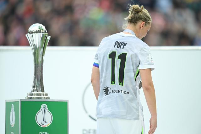 14 May 2026, North Rhine-Westphalia, Cologne: Wolfsburg's Alexandra Popp walks past the championship trophy with her head bowed after the German Women's DFB Cup Final soccer match between VfL Wolfsburg and Bayern Munich at RheinEnergieSTADION. Photo: Fabian Strauch/dpa - WICHTIGER HINWEIS: Gemäß den Vorgaben der DFL Deutsche Fußball Liga bzw. des DFB Deutscher Fußball-Bund ist es untersagt, in dem Stadion und/oder vom Spiel angefertigte Fotoaufnahmen in Form von Sequenzbildern und/oder videoähnlichen Fotostrecken zu verwerten bzw. verwerten zu lassen.
