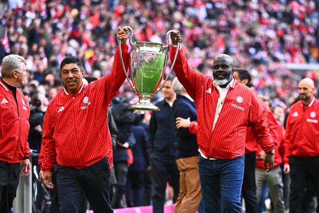 16 May 2026, Bavaria, Munich: Giovane Elber and Samuel Kuffour, members of the 2001 Champions League-winning squad from FC Bayern Munich presents the trophy prior to the start of the German Bundesliga soccer match between Bayern Munich and 1. FC Cologne at Allianz Arena. Photo: Tom Weller/dpa - IMPORTANT NOTICE: DFL and DFB regulations prohibit any use of photographs as image sequences and/or quasi-video.