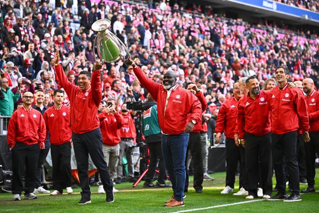 16 May 2026, Bavaria, Munich: Giovane Elber and Samuel Kuffour, members of the 2001 Champions League-winning squad from FC Bayern Munich presents the trophy prior to the start of the German Bundesliga soccer match between Bayern Munich and 1. FC Cologne at Allianz Arena. Photo: Tom Weller/dpa - IMPORTANT NOTICE: DFL and DFB regulations prohibit any use of photographs as image sequences and/or quasi-video.