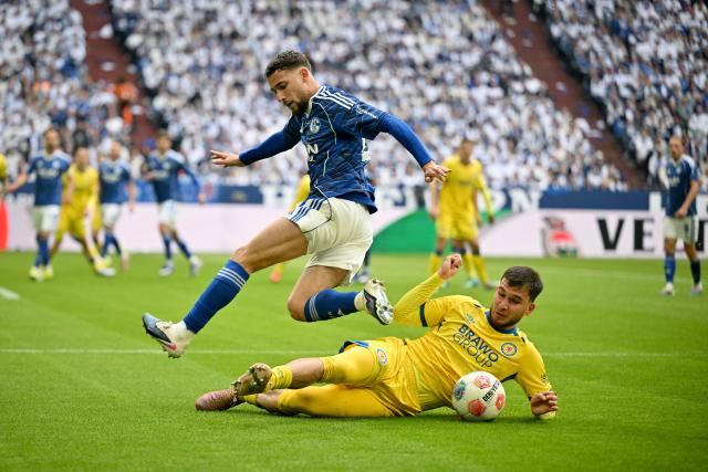 17 May 2026, North Rhine-Westphalia, Gelsenkirchen: Schalke's Adil Aouchiche and Eintracht Braunschweig's Mehmet Aydin battle for the ball during the German 2nd Budnesliga soccer match between FC Schalke 04 and Eintracht Braunschweig at the Veltins Arena Photo: Bernd Thissen/dpa - IMPORTANT NOTICE: DFL and DFB regulations prohibit any use of photographs as image sequences and/or quasi-video.