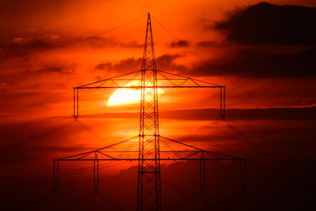 FILED - 04 May 2026, Brandenburg, Biegen: FILE PHOTO - The sun sets behind a high-voltage pylon of a 380 kilovolt (KV) overhead line in Biegen. Photo: Patrick Pleul/dpa