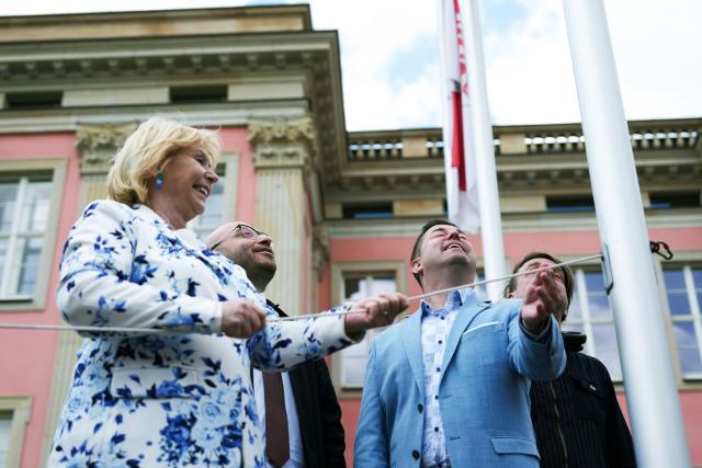18 May 2026, Brandenburg, Potsdam: Ulrike Liedtke (L), President of the Brandenburg State Parliament, raises the rainbow flag in the courtyard of the Brandenburg State Parliament to mark the International Day against Homo-, Bi-, Inter- and Transphobia. Photo: Sven Kaeuler/dpa