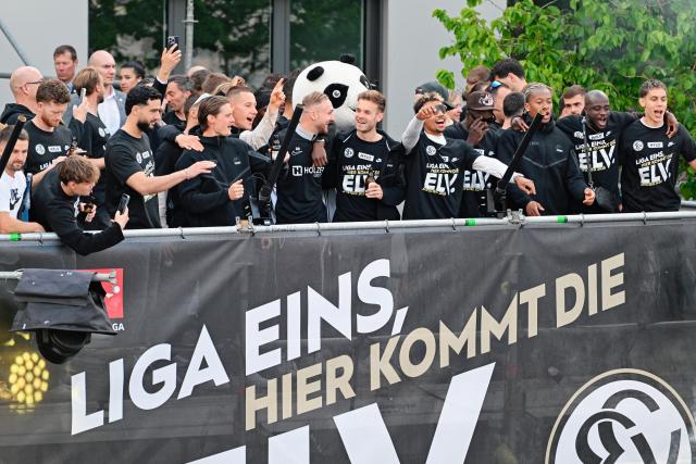 18 May 2026, Saarland, Spiesen-Elversberg: Elversberg team ride on their open-tub bus during a parade celebrating their promotion to the Bundesliga. Photo: Uwe Anspach/dpa - IMPORTANT NOTICE: DFL and DFB regulations prohibit any use of photographs as image sequences and/or quasi-video.