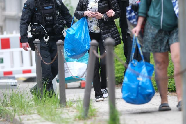20 May 2026, Saxony, Görlitz: Police officers accompany residents of an adjacent building as they retrieve essential items from their apartments, which remain evacuated for safety reasons. The neighbouring Wilhelminian-era property collapsed on 18 May 2026 following a suspected gas explosion, with search teams still clearing the rubble for missing people. Photo: Sebastian Willnow/dpa