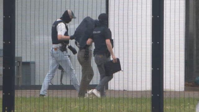 20 May 2026, Baden-Wuerttemberg, Karlsruhe: A suspected Chinese spy is escorted to the Federal Court of Justice (BGH) to appear before an investigating judge in Karlsruhe. The Federal Public Prosecutor's Office ordered the arrest of a couple, both German nationals, in Munich on suspicion of contacting numerous scientists at German universities and research institutes on behalf of a Chinese secret service. Photo: René Priebe/PR-Video /dpa