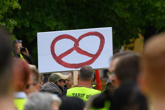 21 May 2026, Saxony-Anhalt, Magdeburg: A pretzel can be seen on the poster of a striker taking part in the rally of the Food, Beverages and Catering Union (NGG). The NGG had called for the central strike rally. Employees from various food businesses took part in the rally on the cathedral square. Photo: Klaus-Dietmar Gabbert/dpa