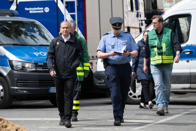 21 May 2026, Saxony, Goerlitz: Octavian Ursu (L), mayor of Goerlitz, and Tobias Sprunk, head of the communications office at the Goerlitz Police Department, walk past the site where two bodies were found near the collapsed apartment building in the city centre. About two days after the building collapse in the eastern German city, the search continues in the rubble for a third missing person Photo: Sebastian Kahnert/dpa