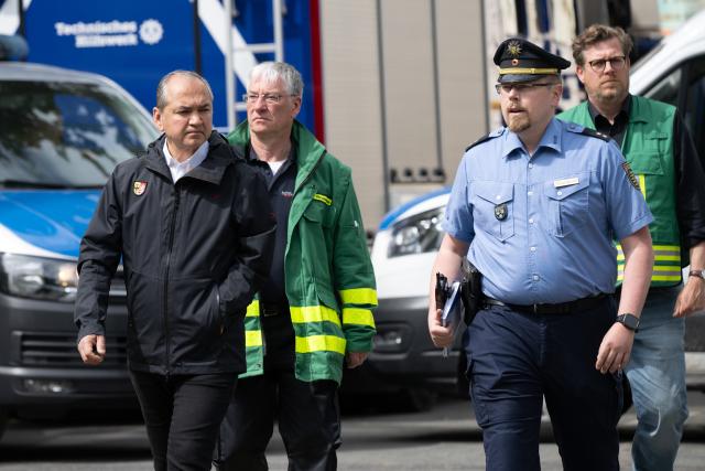 21 May 2026, Saxony, Goerlitz: Octavian Ursu (L), mayor of Goerlitz, and Tobias Sprunk, head of the communications office at the Goerlitz Police Department, walk past the site where two bodies were found near the collapsed apartment building in the city centre. About two days after the building collapse in the eastern German city, the search continues in the rubble for a third missing person Photo: Sebastian Kahnert/dpa