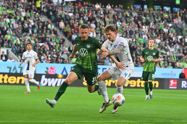 21 May 2026, Lower Saxony, Wolfsburg: Wolfsburg's Yannick Gerhardt (L) and Paderborn's Calvin Brackelmann (R) battle for the ball during the German Bundesliga relegation playoff soccer match between VfL Wolfsburg and SC Paderborn 07 at Volkswagen Arena. Photo: Swen Pförtner/dpa - WICHTIGER HINWEIS: Gemäß den Vorgaben der DFL Deutsche Fußball Liga bzw. des DFB Deutscher Fußball-Bund ist es untersagt, in dem Stadion und/oder vom Spiel angefertigte Fotoaufnahmen in Form von Sequenzbildern und/oder videoähnlichen Fotostrecken zu verwerten bzw. verwerten zu lassen.