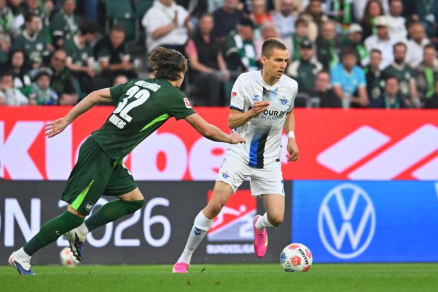 21 May 2026, Lower Saxony, Wolfsburg: Paderborn's Filip Bilbija (R) and Wolfsburg's Mattias Svanberg (L) battle for the ball during the German Bundesliga relegation playoff soccer match between VfL Wolfsburg and SC Paderborn 07 at Volkswagen Arena. Photo: Swen Pförtner/dpa - WICHTIGER HINWEIS: Gemäß den Vorgaben der DFL Deutsche Fußball Liga bzw. des DFB Deutscher Fußball-Bund ist es untersagt, in dem Stadion und/oder vom Spiel angefertigte Fotoaufnahmen in Form von Sequenzbildern und/oder videoähnlichen Fotostrecken zu verwerten bzw. verwerten zu lassen.