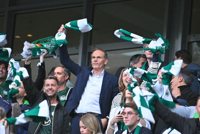 21 May 2026, Lower Saxony, Wolfsburg: VW CEO Oliver Blume waves a Wolfsburg scarf from the stands during the German Bundesliga relegation playoff soccer match between VfL Wolfsburg and SC Paderborn 07 at Volkswagen Arena. Photo: Swen Pförtner/dpa - WICHTIGER HINWEIS: Gemäß den Vorgaben der DFL Deutsche Fußball Liga bzw. des DFB Deutscher Fußball-Bund ist es untersagt, in dem Stadion und/oder vom Spiel angefertigte Fotoaufnahmen in Form von Sequenzbildern und/oder videoähnlichen Fotostrecken zu verwerten bzw. verwerten zu lassen.