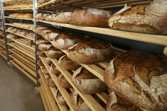 21 May 2026, Schleswig-Holstein, Kiel: Bread is stored on a shelf at a bakery in Kiel. David Schoene, a baker from Kiel, is opening a so-called "sourdough hotel" at his bakery on Saturday. Customers can store their sourdough on this wooden shelf for a limited time so it can be cared for if they are unable to tend to it themselves while away. Photo: Frank Molter/dpa