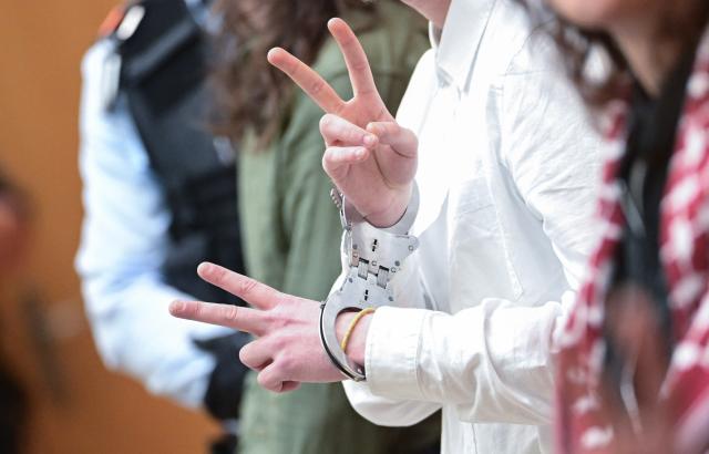 22 May 2026, Baden-Württemberg, Stuttgart: A Defendant gestures the V sign during a trial for an attack against an Israeli arms company. Five pro-Palestine activists are on trial. According to the indictment, they broke into an Israeli arms company in Ulm at night, destroyed inventory, sprayed the walls and caused millions in damage. Photo: Bernd Weißbrod/dpa