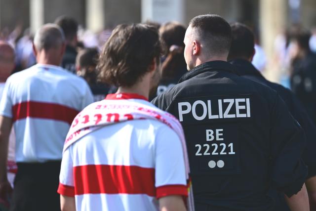 23 May 2026, Berlin: A police officer walks among the fans ahead of the German DFB Cup Final soccer match between Bayern Munich andVfB Stuttgart at Berlin Olympic Stadium. Photo: Sebastian Gollnow/dpa