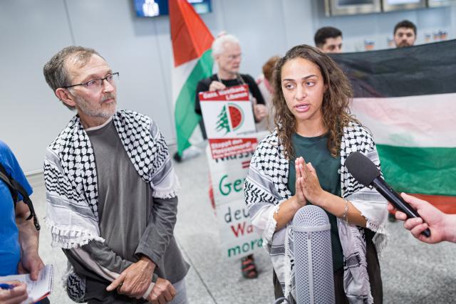 23 May 2026, Lower Saxony, Langenhagen: Uwe Sander and Nesrin Zeaiter give interviews while standing in front of their supporters at Hanover Airport. The two activists from the Gaza aid flotilla, who were deported from Israel to Turkey, have returned to Germany. Photo: Moritz Frankenberg/dpa