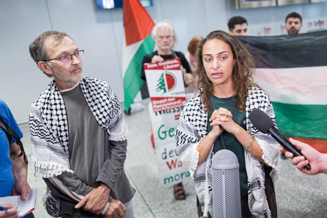 23 May 2026, Lower Saxony, Langenhagen: Uwe Sander and Nesrin Zeaiter give interviews while standing in front of their supporters at Hanover Airport. The two activists from the Gaza aid flotilla, who were deported from Israel to Turkey, have returned to Germany. Photo: Moritz Frankenberg/dpa