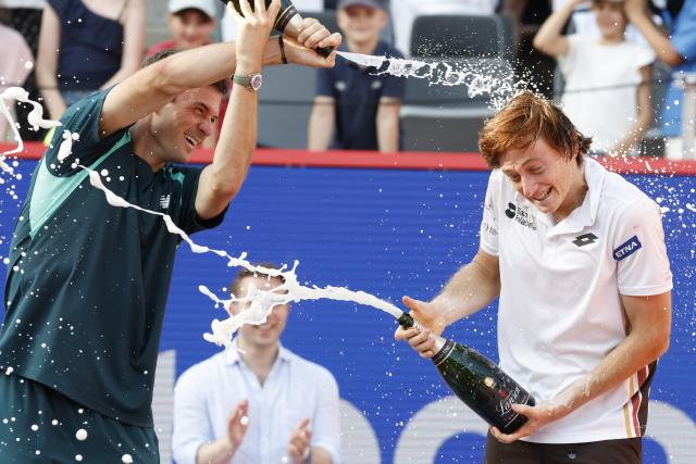 23 May 2026, Hamburg: American tennis player Tommy Paul (L) and winner Peru's Ignacio Buse (R) are doused with champagne during the award ceremony after the men's singles final of the Hamburg Open tennis tournament. Photo: Georg Wendt/dpa