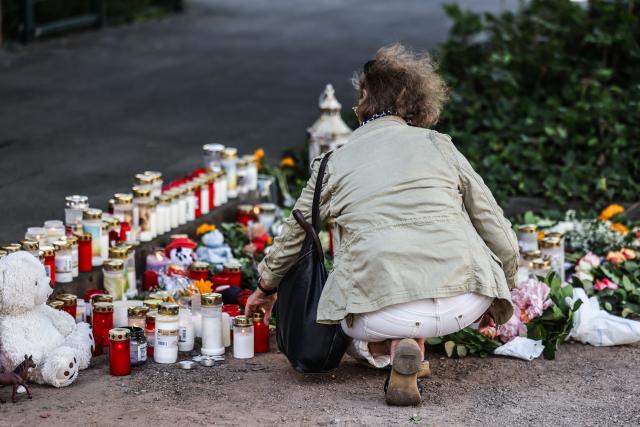 28 May 2026, North Rhine-Westphalia, Dinslaken: A woman lays a candle at the scene of the accident, where a 47-year-old woman hit three children with her car, two of whom died. Photo: Oliver Berg/dpa