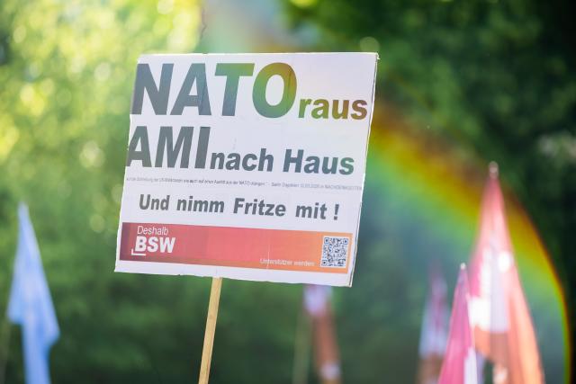 28 May 2026, Berlin: 'NATO out, Americans go home' reads a sign at a rally organized by the Sahra Wagenknecht Alliance (BSW) at Lucie-Leydicke-Platz in Berlin-Schöneberg. Ahead of the Berlin House of Representatives election on September 20, 2026, the BSW is holding a rally and inviting attendees to join party founder Wagenknecht for a visit to a local pub. Photo: Christoph Soeder/dpa