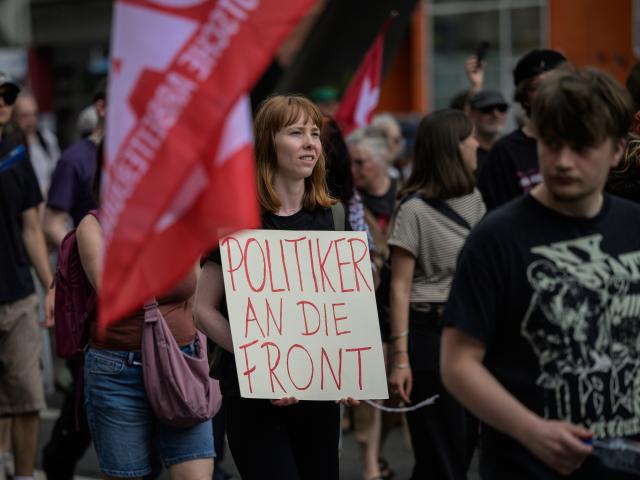 30 May 2026, Hesse, Wiesbaden: A protester holds a sign reading "Politicians to the front" during a demonstration outside the US Ramstein Air Base in southwestern Germany. The activists gathered to protest against the deployment of medium-range missiles and the utilization of American military facilities for foreign conflicts. Photo: Hannes P. Albert/dpa