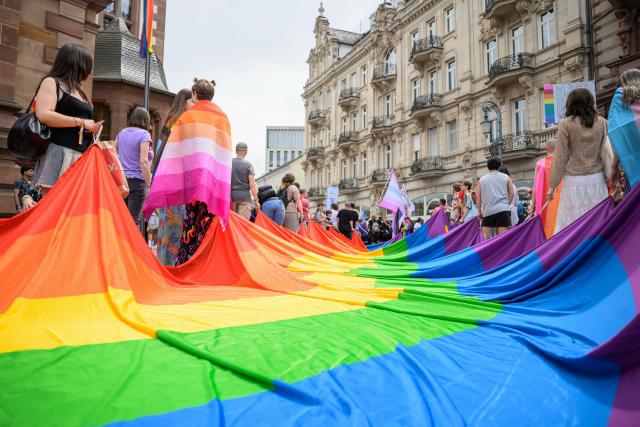 30 May 2026, Hesse, Wiesbaden: Demonstrators hold a large rainbow flag during the Christopher Street Day event in Wiesbaden. According to the organizers, the group "Warmes Wiesbaden" plans to use Saturday's Pride event to stand up for an open society and against discrimination and anti-queer sentiment. Photo: Hannes P. Albert/dpa
