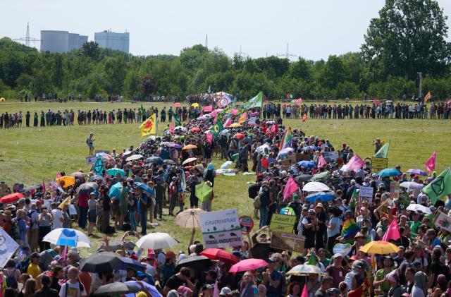 30 May 2026, North Rhine-Westphalia, Hamm: Demonstrators form a wind turbine against the backdrop of a power plant. A climate alliance consisting of Fridays for Future, Greenpeace, BUND and Campact has called for the rally under the motto "Future instead of gas - defending the energy transition". Photo: Bernd Thissen/dpa