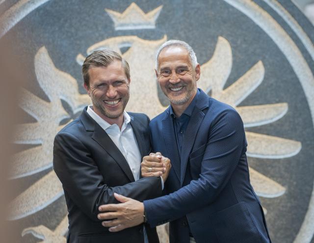 01 June 2026, Hesse, Frankfurt/Main: Markus Kroesche (L), sporting director of German Bundesliga soccer club Eintracht Frankfurt, and incoming head coach Adi Huetter stand in front of the stone Eintracht eagle at the club's training camp. Eintracht Frankfurt introduced its new head coach Adi Huetter at a press conference, with Huetter set to take charge of the club for the second time in his career starting July 1, 2026. Photo: Andreas Arnold/dpa - WICHTIGER HINWEIS: Gemäß den Vorgaben der DFL Deutsche Fußball Liga bzw. des DFB Deutscher Fußball-Bund ist es untersagt, in dem Stadion und/oder vom Spiel angefertigte Fotoaufnahmen in Form von Sequenzbildern und/oder videoähnlichen Fotostrecken zu verwerten bzw. verwerten zu lassen.