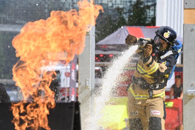 03 June 2026, Lower Saxony, Hannover: Firefighter Stefanie Fitzner extinguishes a small fire at the Interschutz trade fair as part of the Firefit European Championship competition. Interschutz is the leading international trade fair for fire and disaster protection, rescue and safety. Photo: Julian Stratenschulte/dpa