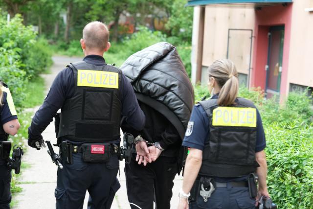 03 June 2026, Berlin: Berlin police lead a man away in handcuffs in Hellersdorf after a man who was reportedly seen with a weapon was arrested there. A resident of an apartment building informed police that he had seen a man with a weapon, who then returned to his apartment on Oschatzer Ring. Photo: Sven Kaeuler/dpa
