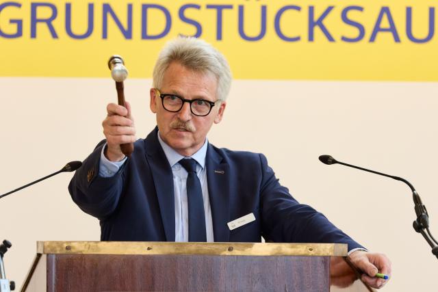 04 June 2026, Hamburg: Auctioneer Thomas Knopp stands at the auction podium during a sale in the Reimarus Hall at the Haus der Patriotischen Gesellschaft. The artificial island from the GDR era, "Ostervilm," was put up for auction with a minimum bid of 39,000 euros. Photo: Georg Wendt/dpa