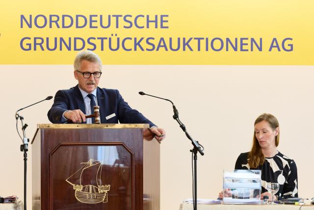 04 June 2026, Hamburg: Auctioneer Thomas Knopp stands at the auction podium during a sale in the Reimarus Hall at the Haus der Patriotischen Gesellschaft. The artificial island from the GDR era, "Ostervilm," was put up for auction with a minimum bid of 39,000 euros. Photo: Georg Wendt/dpa