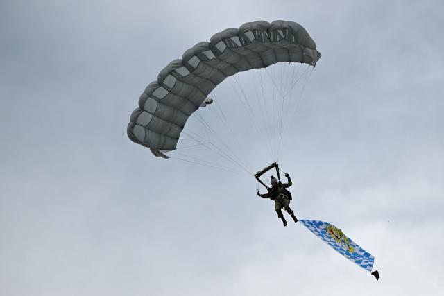 06 June 2026, Bavaria, Neubiberg: A Bundeswehr parachutist lands  on the grounds of the German Armed Forces (Bundeswehr) University during the Bundeswehr Day. Photo: Sven Hoppe/dpa